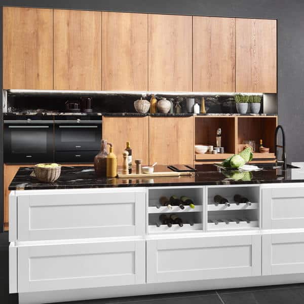 Eine Küche mit zwei Küchenfronten. Die Einbauschränke aus hellem Holz und die Küchentheke in weiß.